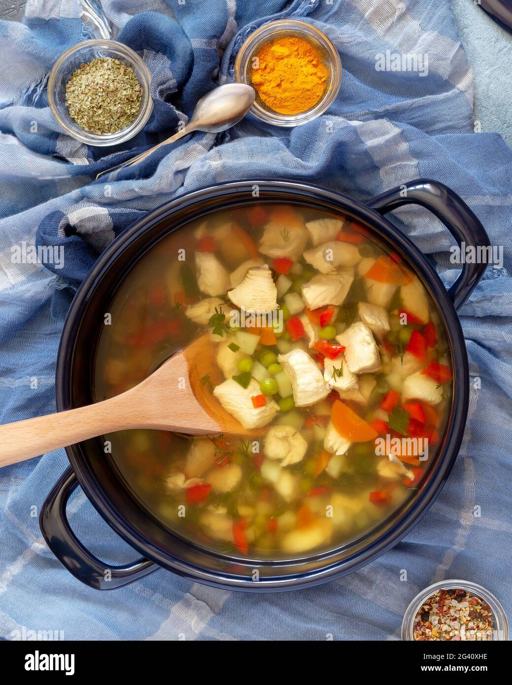 Jewish national cuisine. Vertical food composition with large pot with hot Jewish chicken soup and spices on a blue background. Healthy and tasty food Stock Photo