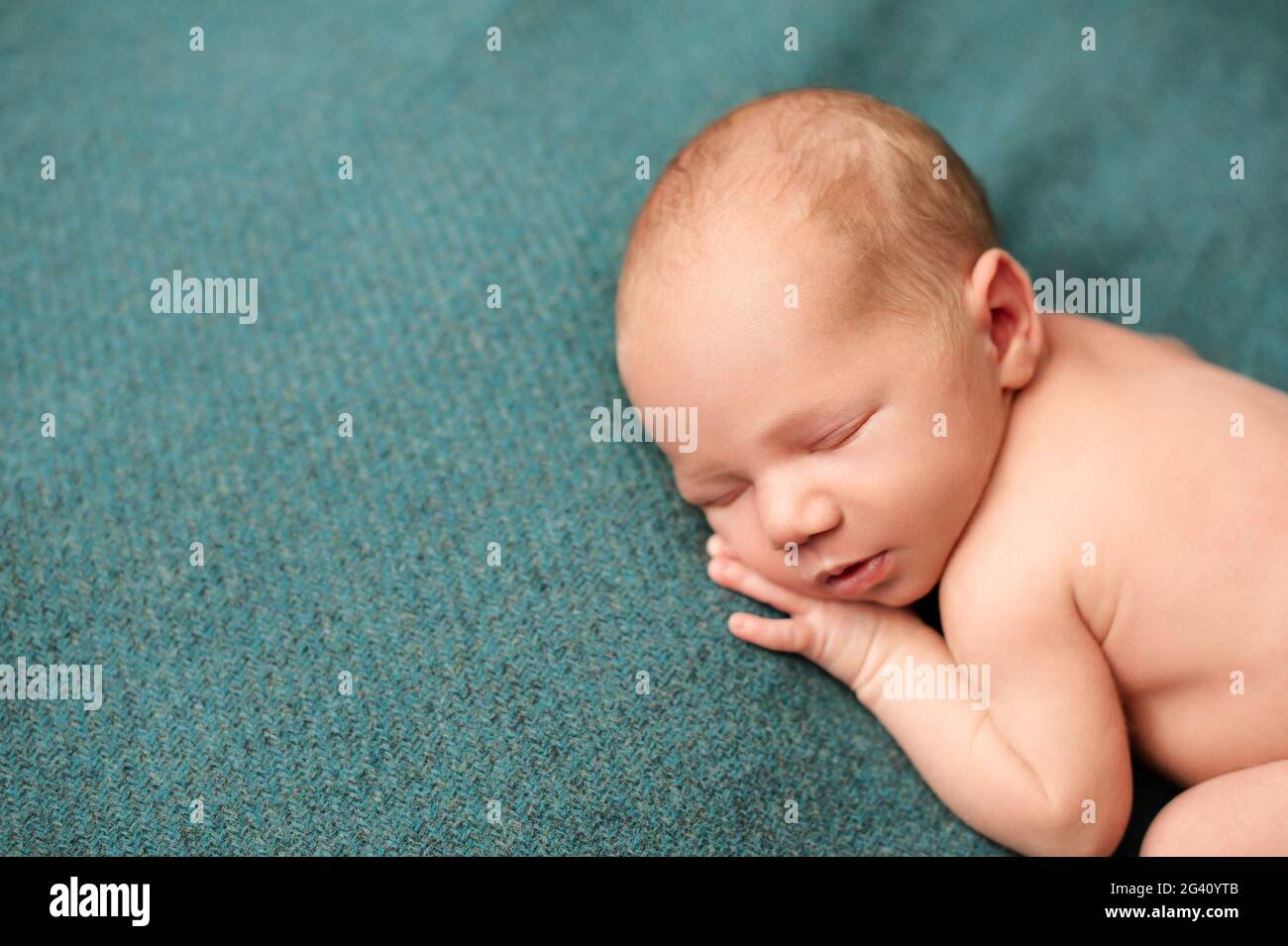 Portrait of a newborn sleeping with his hands under his cheeks on a