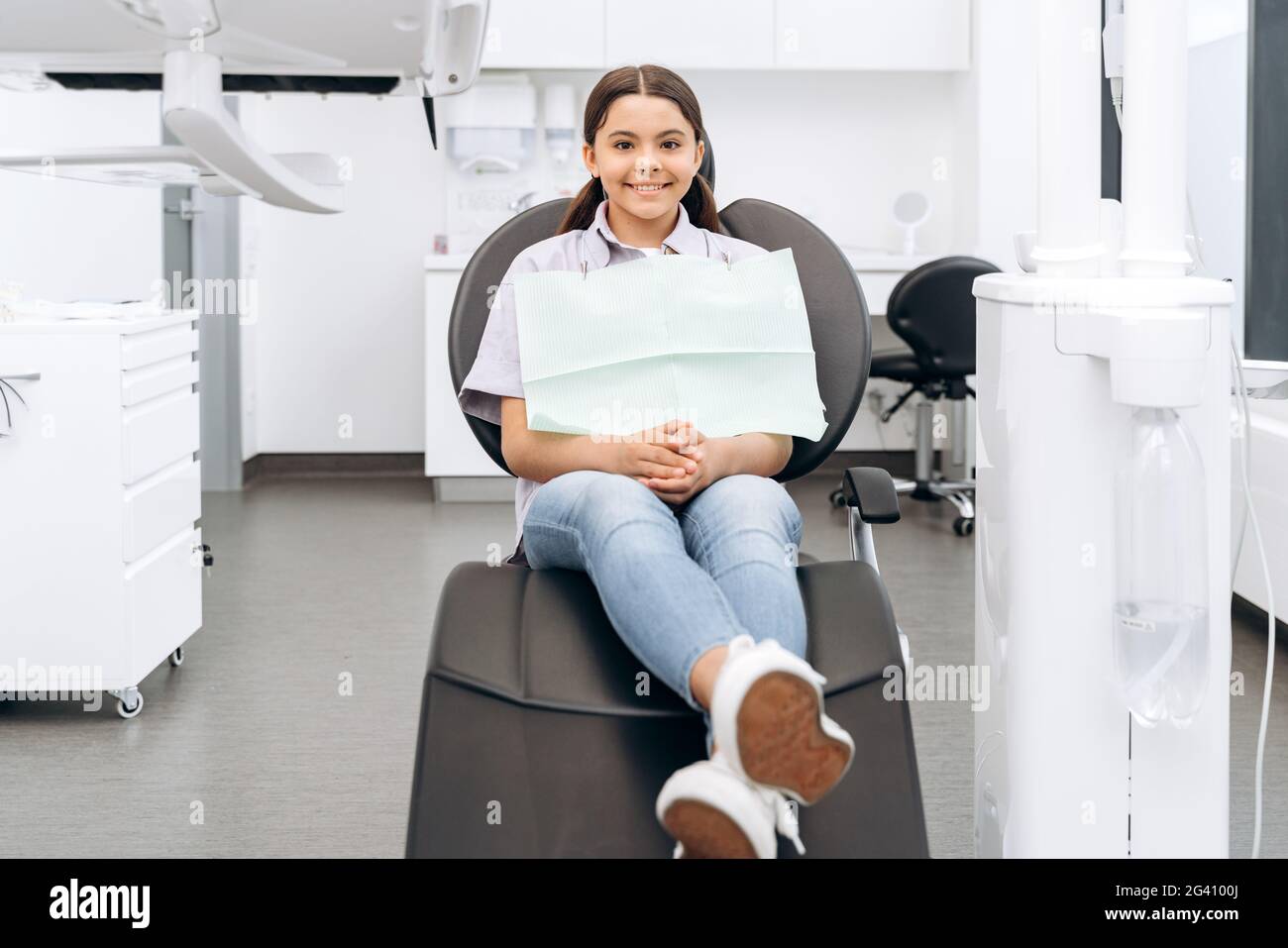Pleasant, young patient is waiting for a doctor in a dental chair. Cute, young patient smiling. Stock Photo