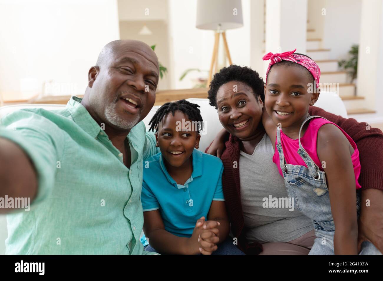 African american grandfather and grandmother on couch smiling with grandchildren taking selfie Stock Photo