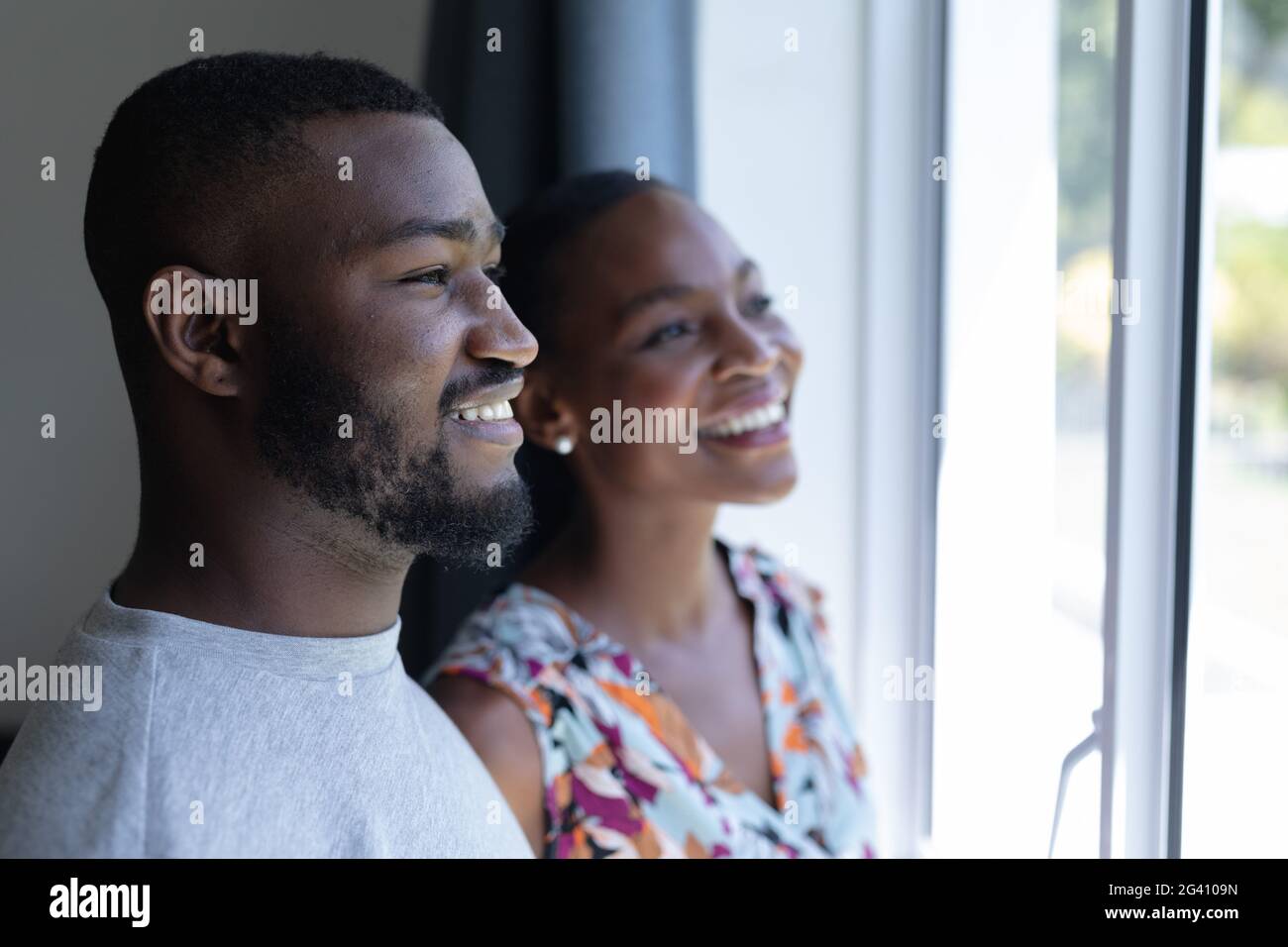Happy african american couple standing looking out of window and ...