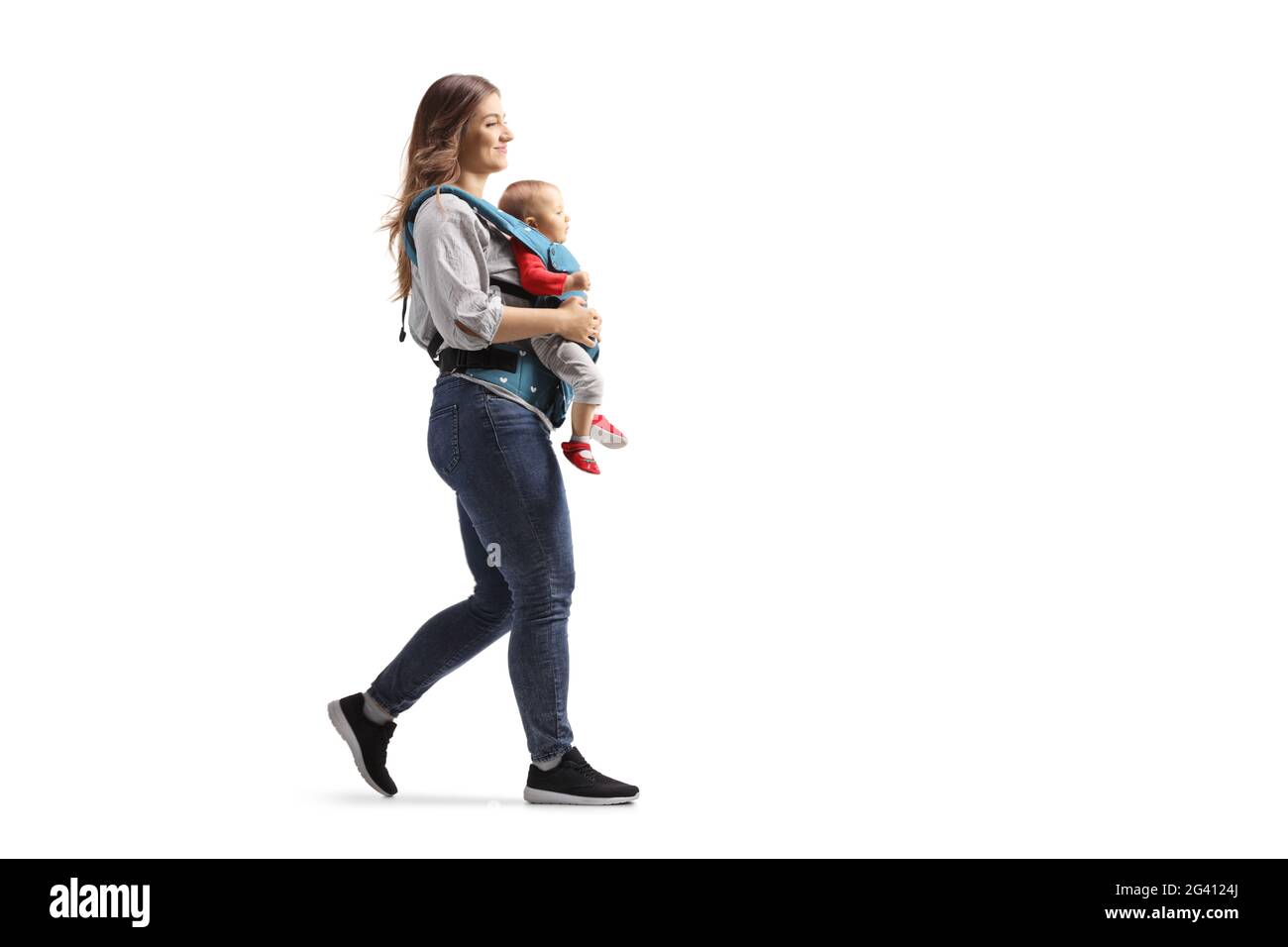 Full length profile shot of a mother walking and carrying a baby in a carrier solated on white background Stock Photo