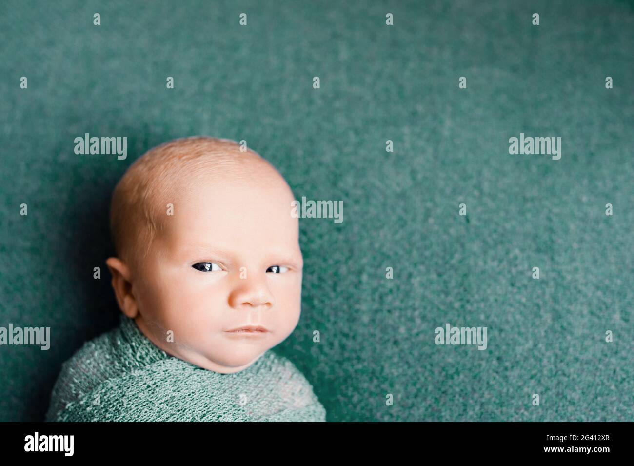 Newborn baby boy wrapped in a knitted turquoise blanket looking into the camera Stock Photo Alamy