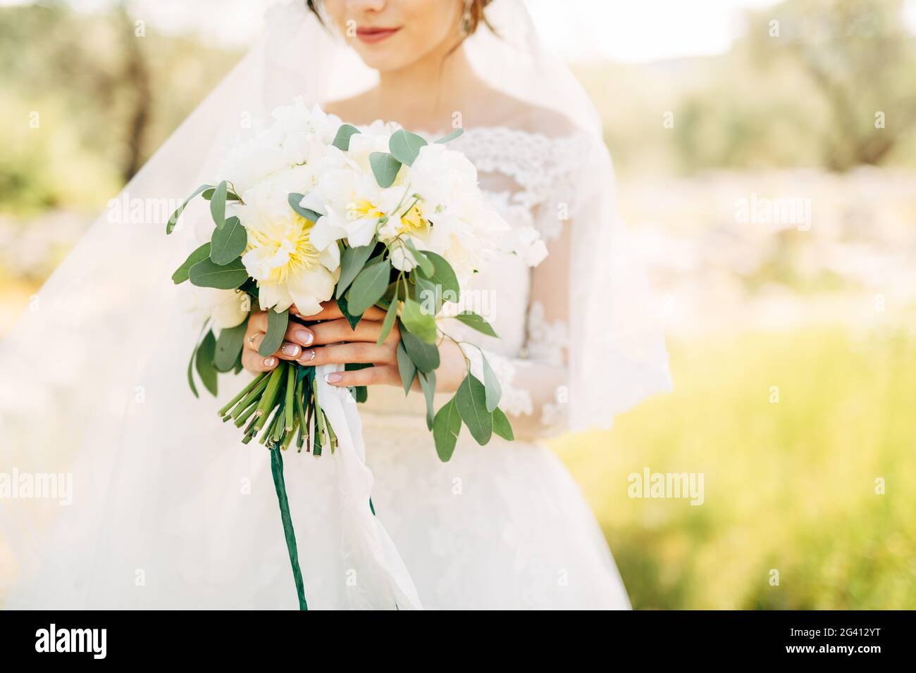 Beautiful bride in tender wedding dress holding bridal bouquet in her hands Stock Photo