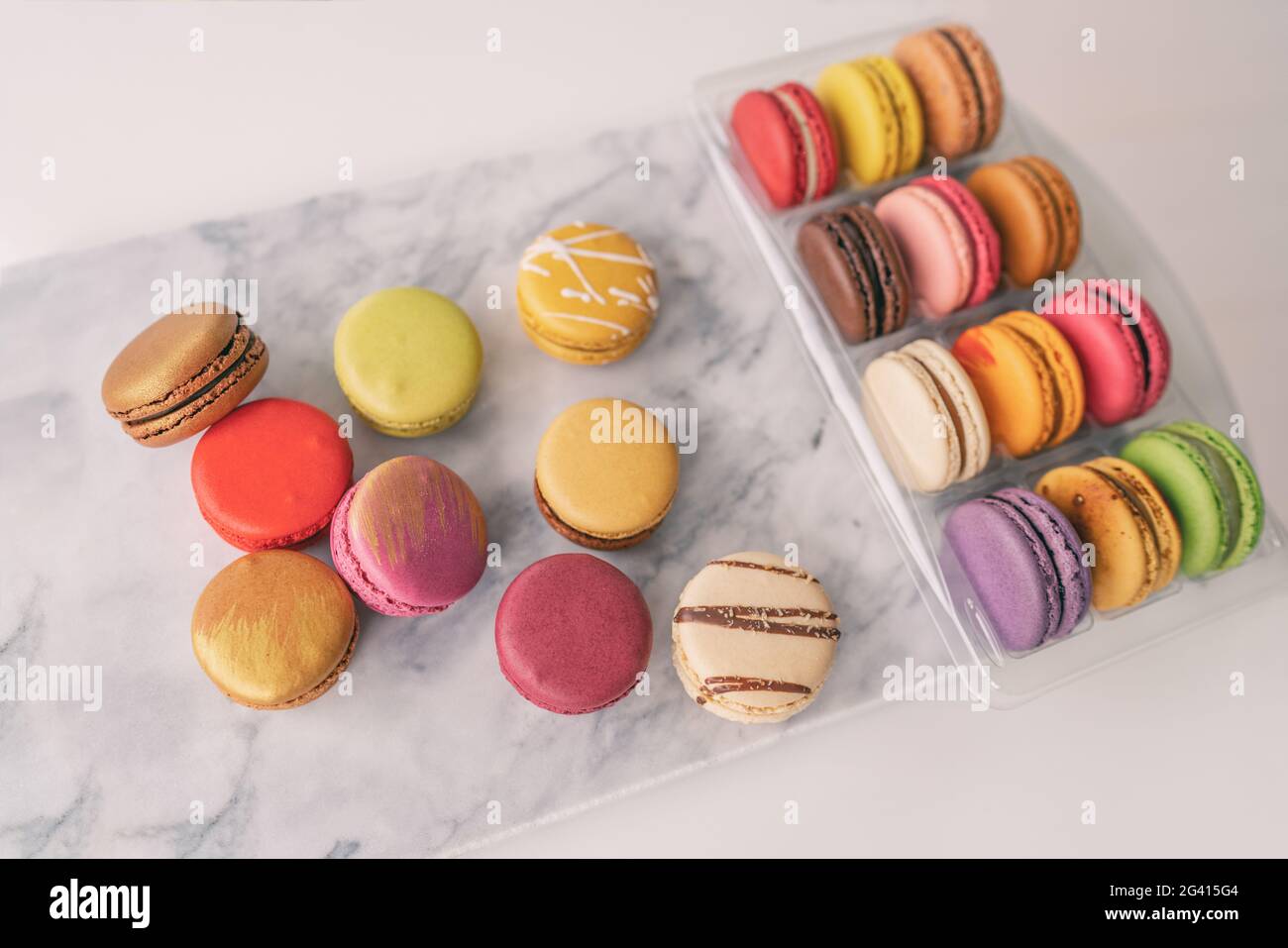 Top view of french macarons gift box macaroons wrapped in giftbox on marble board tabletop. Colorful selection of pastries Stock Photo