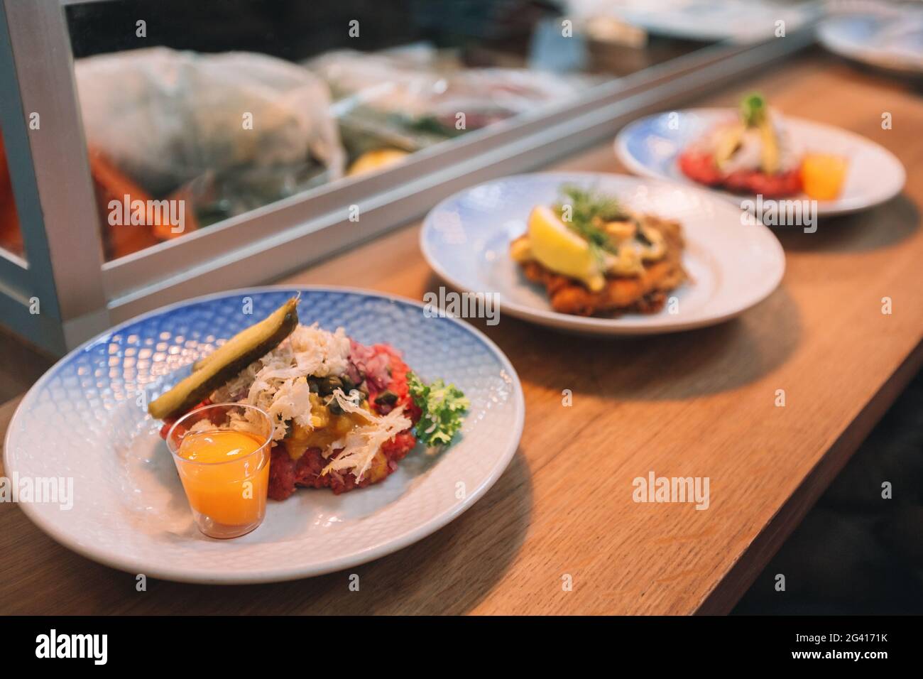 Copenhagen restaurant counter table plates with beef tartare and fish smorrebrod open faced sandwich. Traditional Danish food in Denmark travel Stock Photo