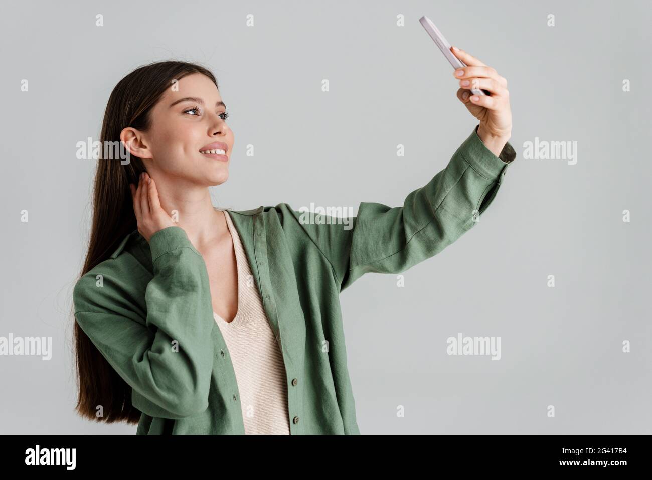 Happy caucasian girl smiling and taking selfie on mobile phone isolated ...