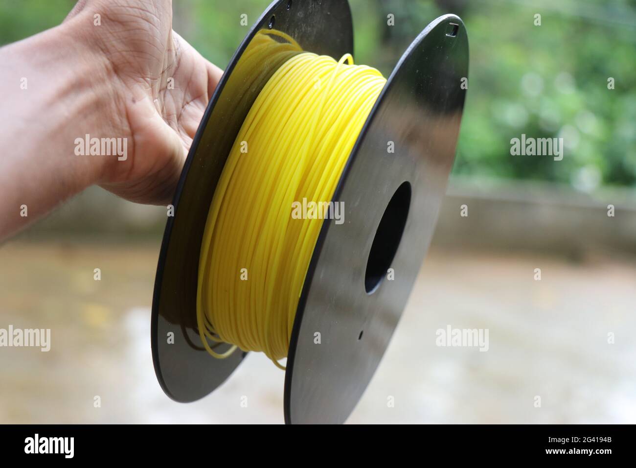 Filaments used in 3d printer on a spool held in hand. Stock Photo