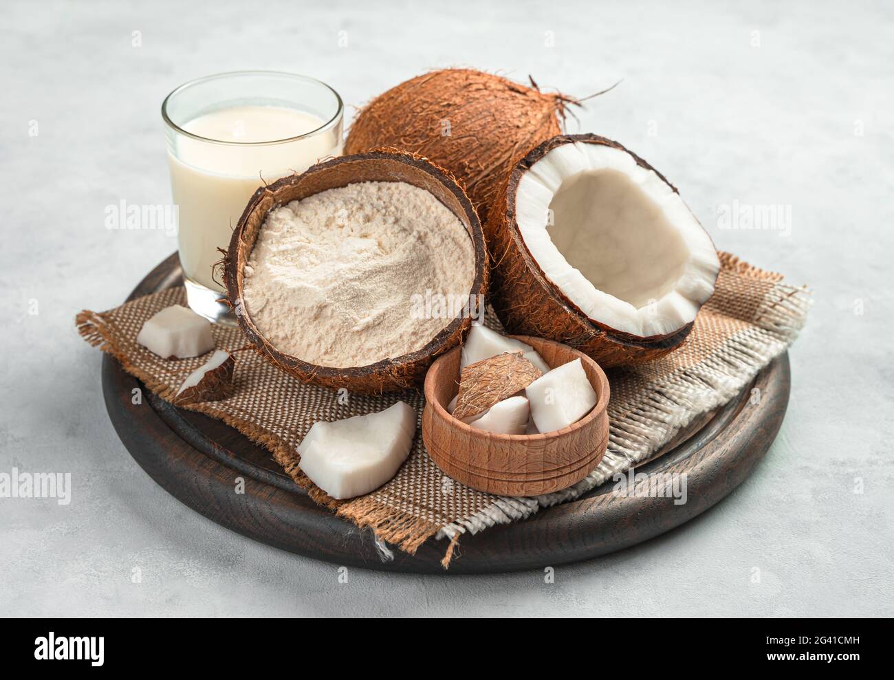 Coconut flour, coconut milk and fresh opened coconut on a gray