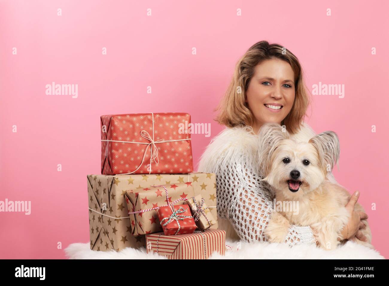 https://c8.alamy.com/comp/2G41FME/mature-woman-with-cute-dog-beside-christmas-presents-2G41FME.jpg