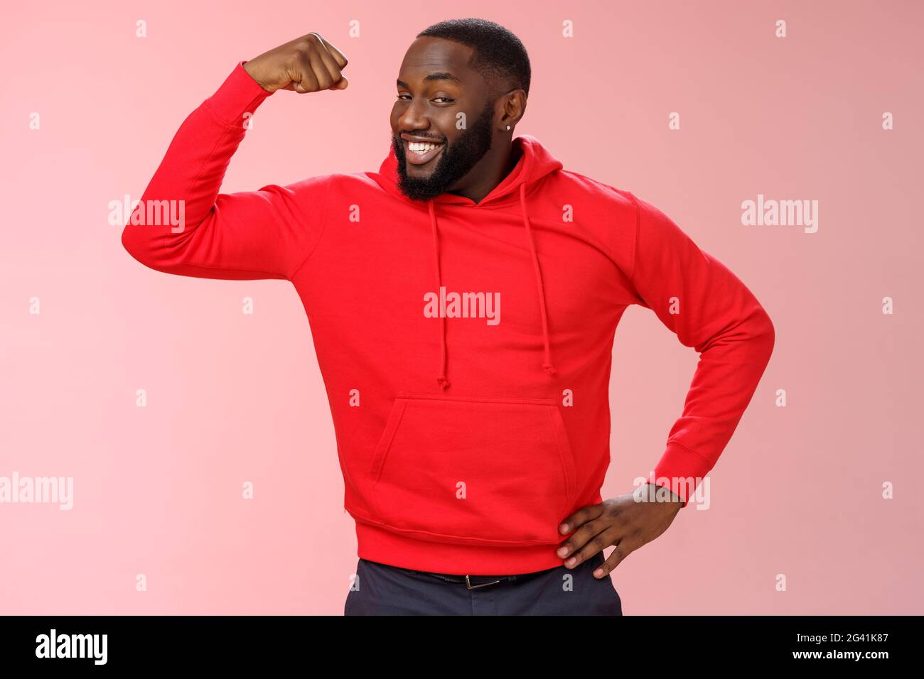 Charming cheeky friendly african-american strong guy smiling broadly proudly showing biceps raise one hand bragging muscles atte Stock Photo