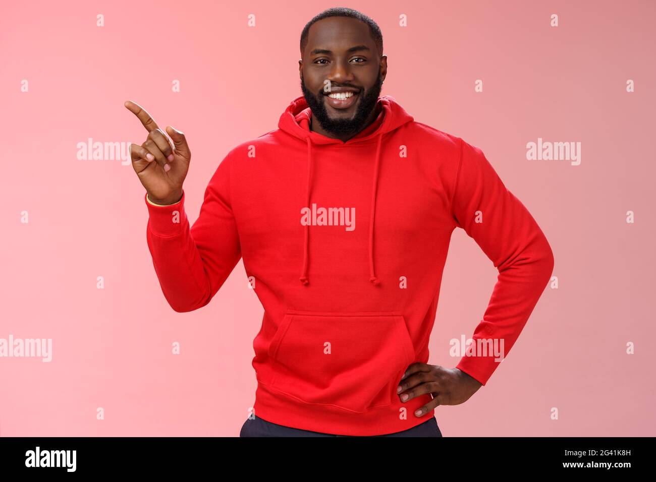 Handsome friendly-looking black guy bearded wearing casual red hoodie pointing left help customer find way directing blank space Stock Photo
