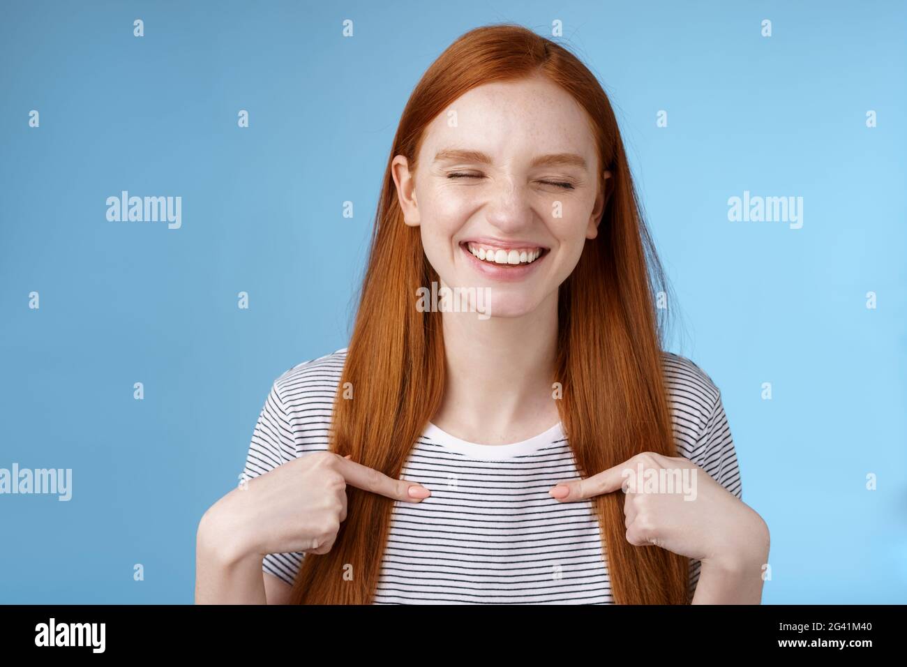 Happy cheerful glad young sportswoman redhead nominated smiling surprised laughing joyfully close eyes pointing herself chosen p Stock Photo
