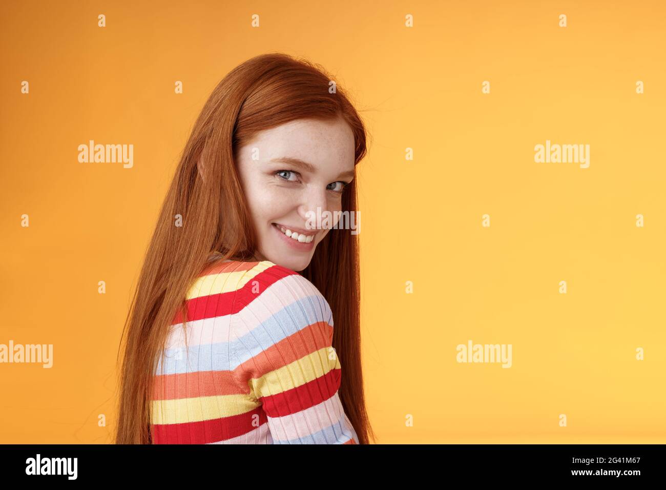 Tenderness, romance, seduction concept. Attractive cheeky flirty young redhead daring girl turn behind look shoulder camera smil Stock Photo
