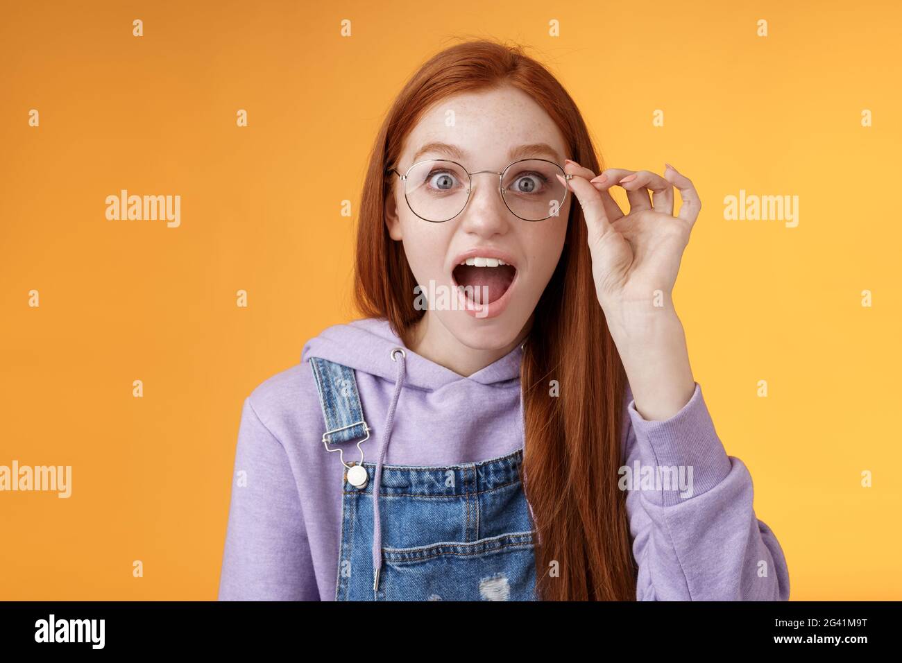 Omg so cool. Portrait amazed speechless excited redhead girl drop jaw amused stare camera surprised find out awesome product net Stock Photo