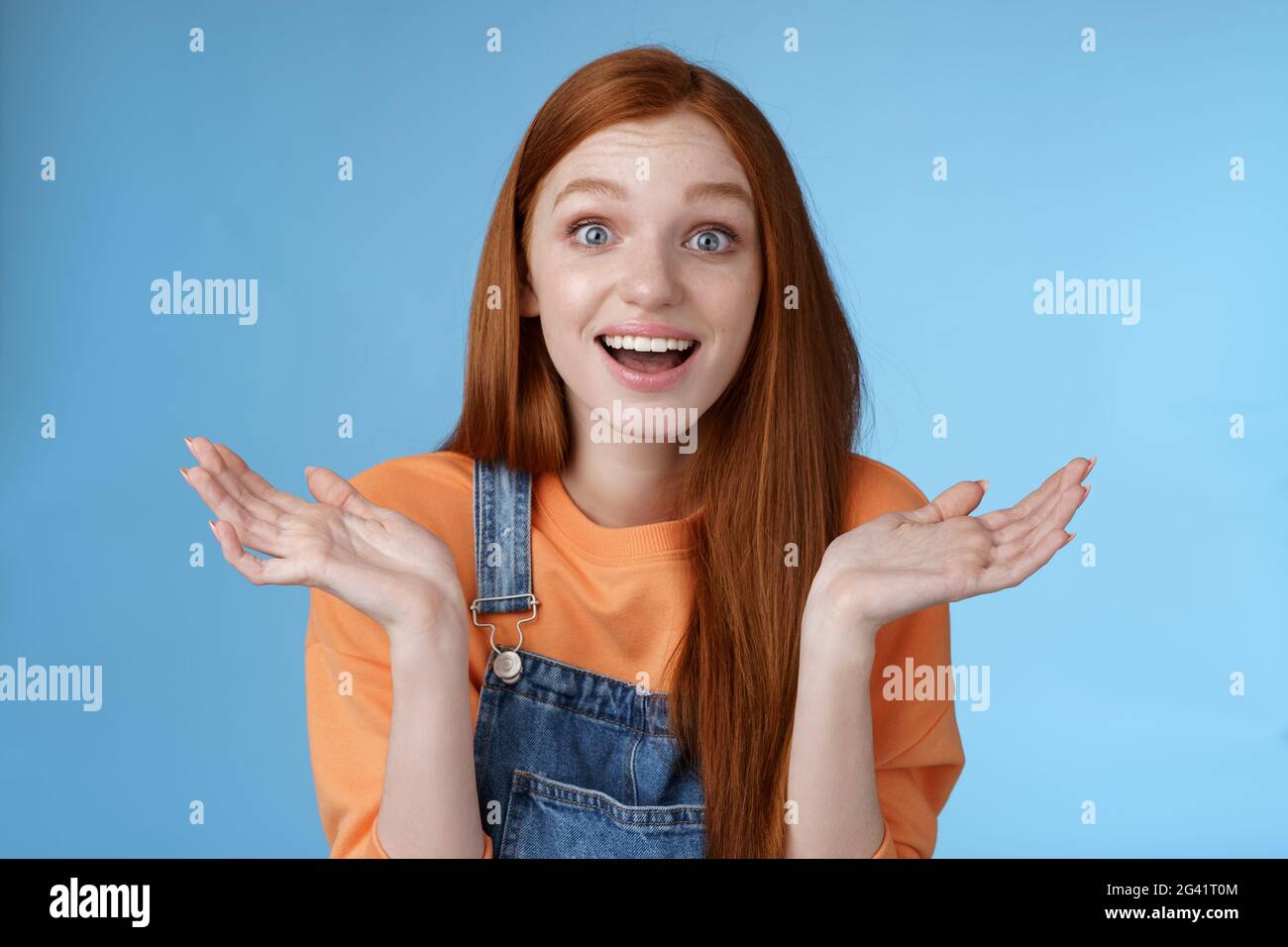 Amused surprised glad young redhead girl speechless happy see friend came back hometown wide eyes impressed grinning raise hands Stock Photo