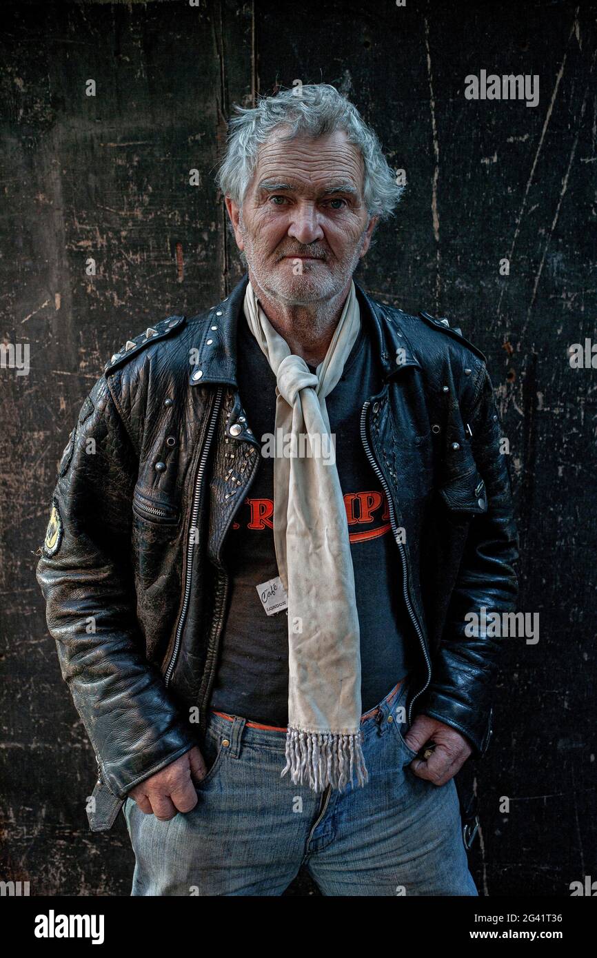 Mature Rocker wearing leather jacket and white scarf in London , England. Stock Photo