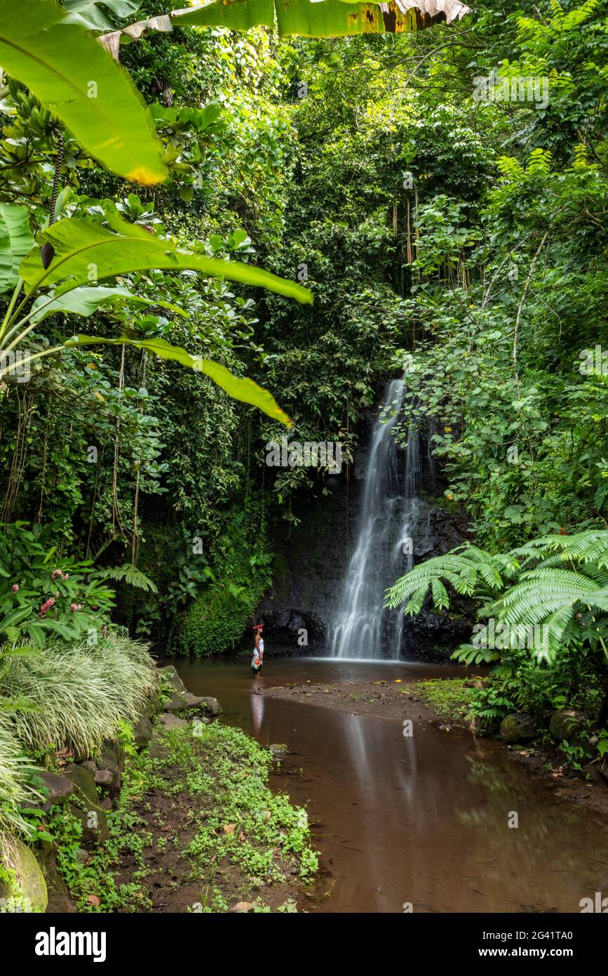 Beautiful young Tahitian woman in front of waterfall in 'The Water