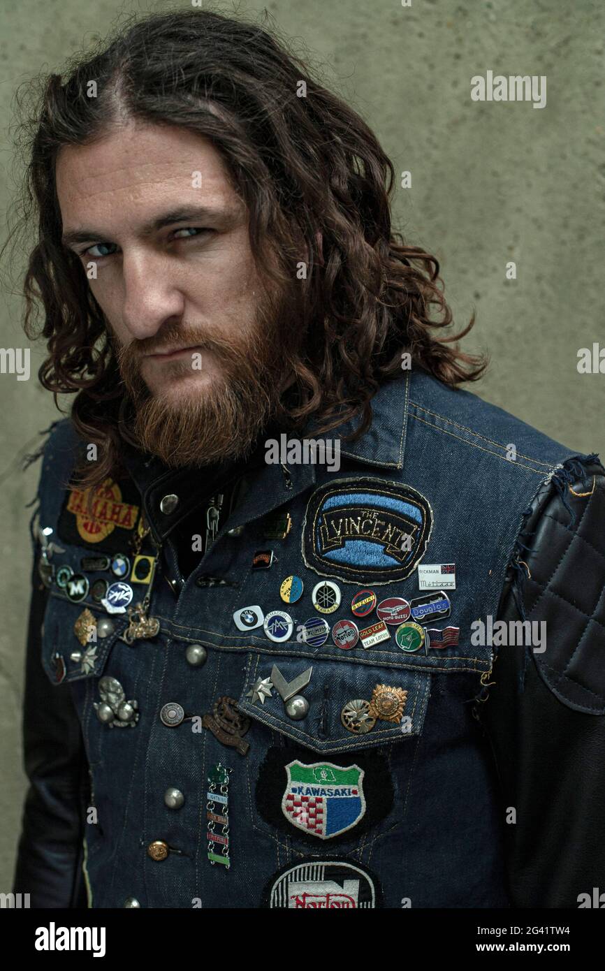 Portrait of a bearded Rocker with denim jeans vest with patches . Rocker Denim Jean Vest Jacket . Stock Photo