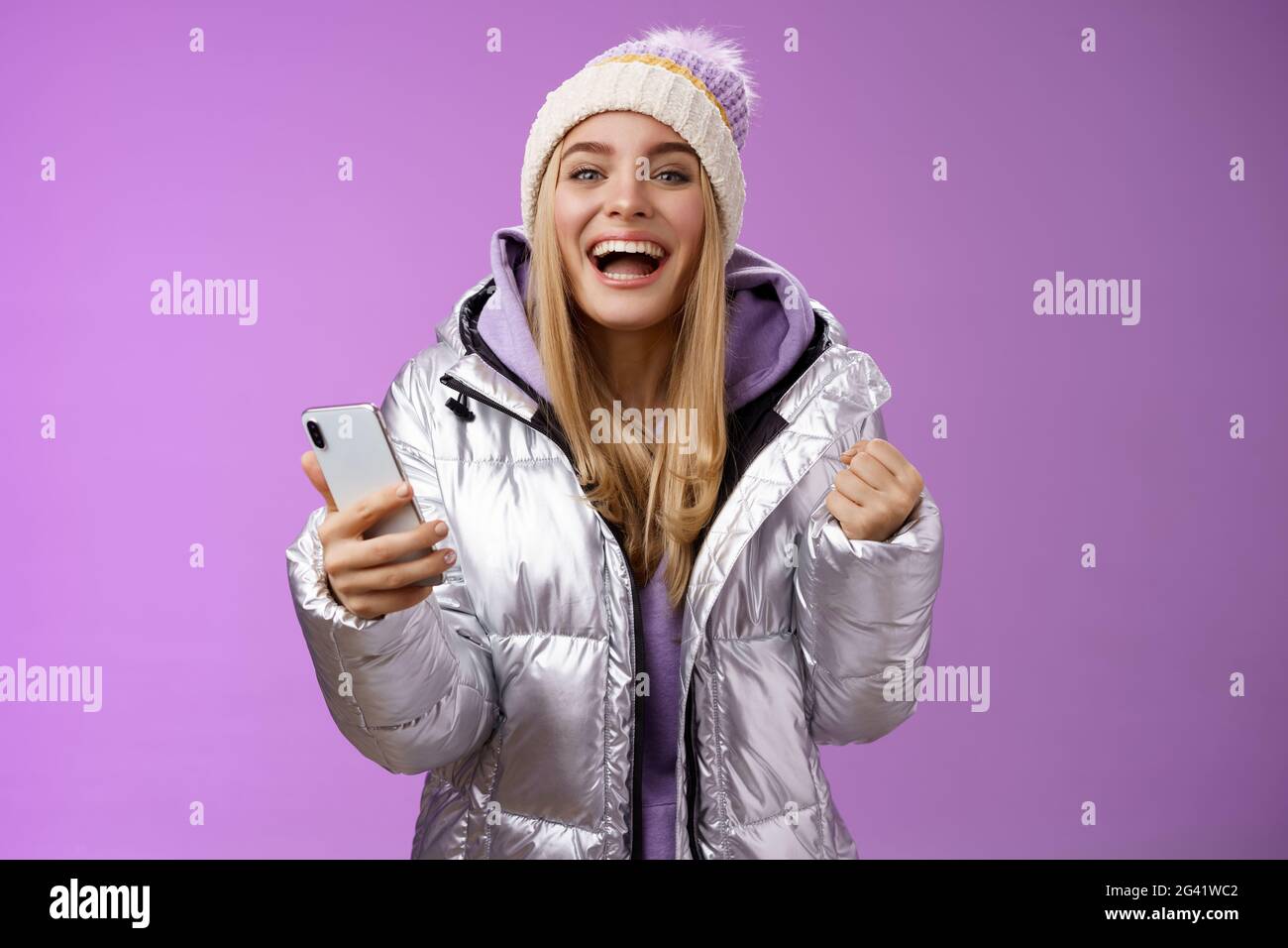 Happy lucky charming blond triumphing girl winning lottery first prize receive good news message smartphone clench fists celebra Stock Photo