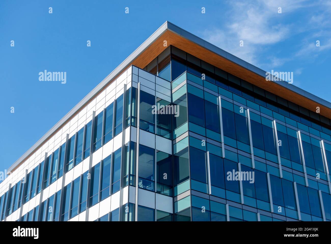 Angled view of a large, window covered building corner against a blue, cloud filled sky Stock Photo