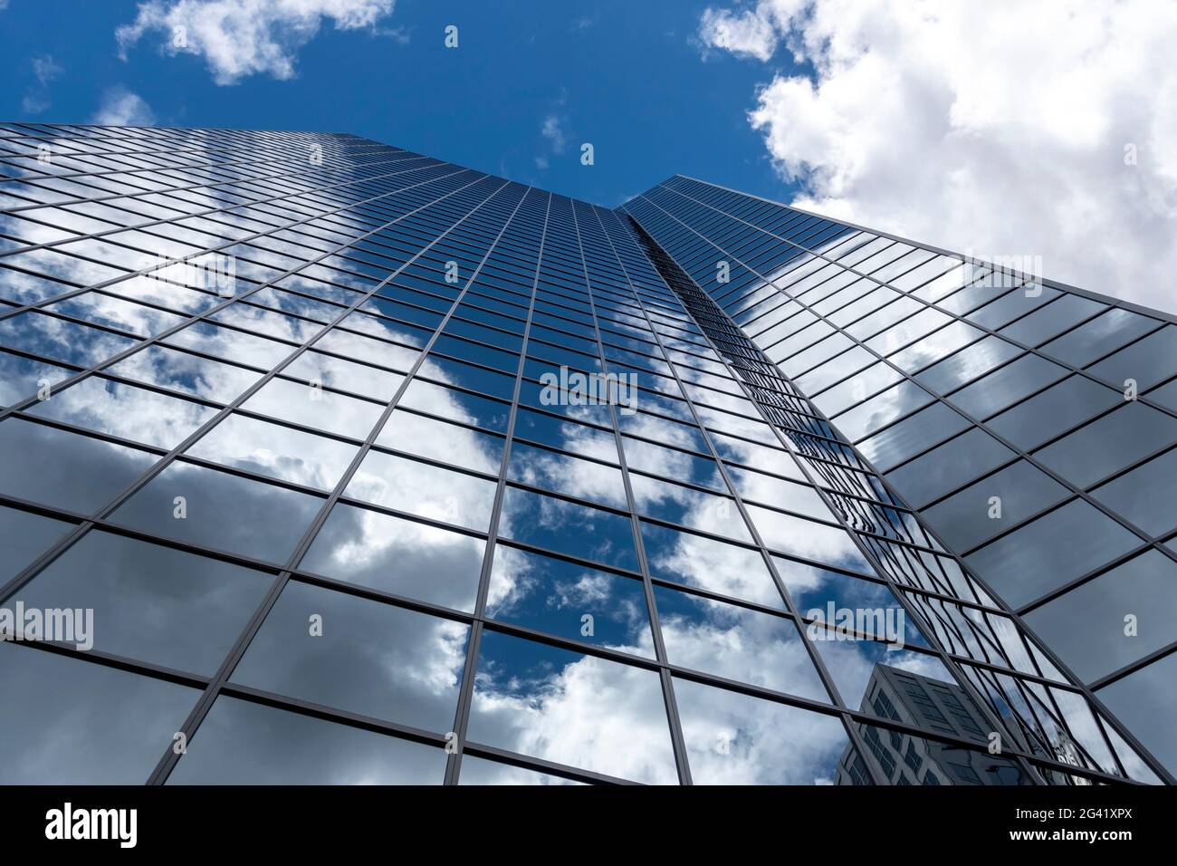Angled view of a large, window covered building corner against a blue, cloud filled sky Stock Photo