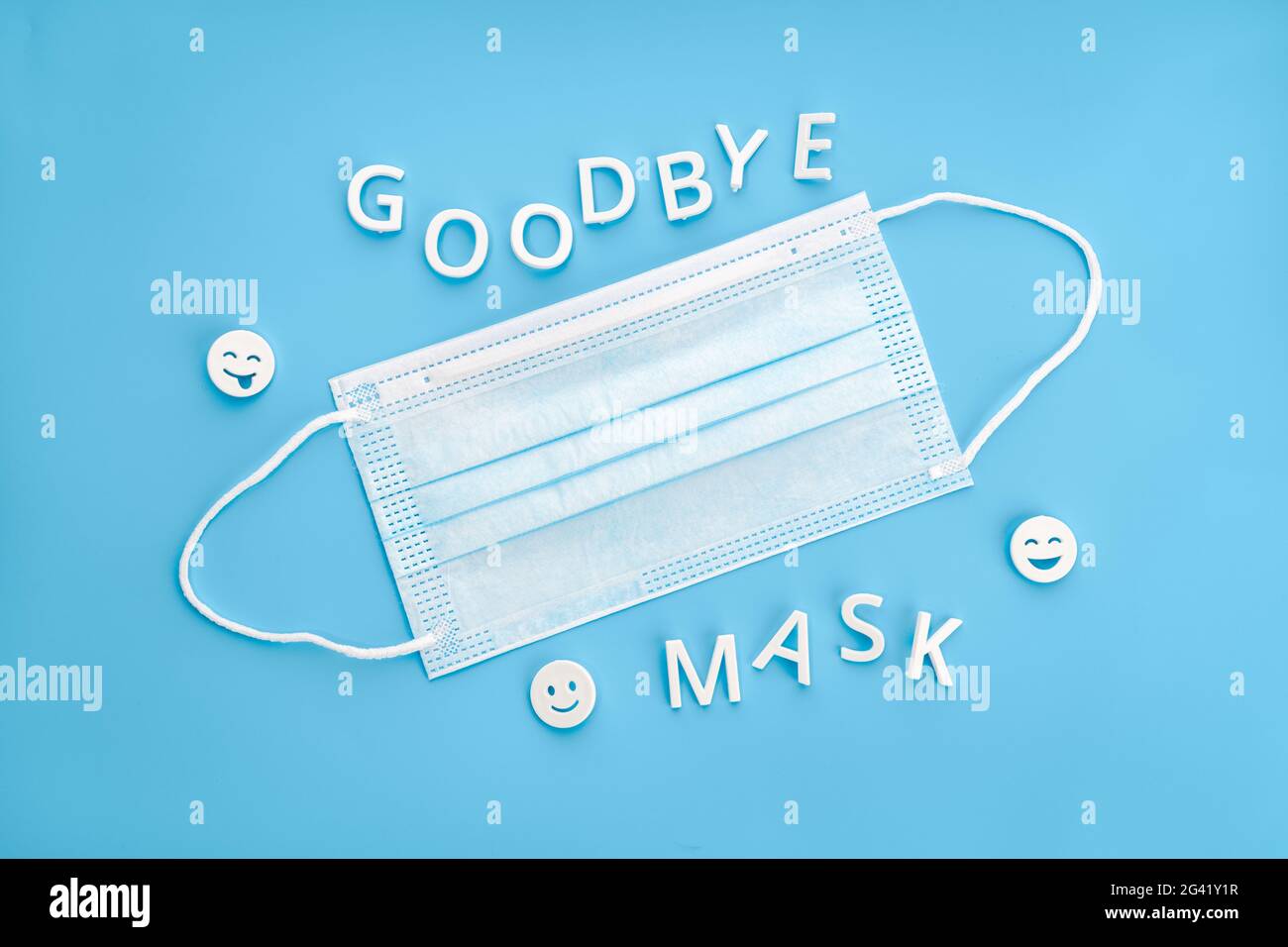 Goodbye mask phrase and face mask isolated on blue background. Concept of no longer be required to wear face masks Stock Photo