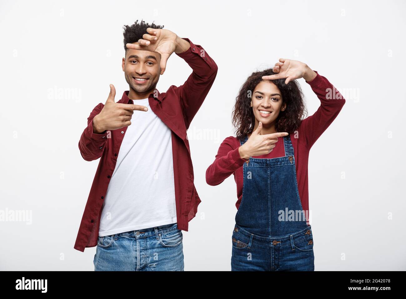 Happy young African American couple looking through a finger frame and smiling while standing isolated on white. Stock Photo