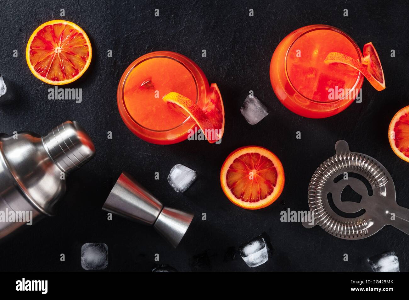 Orange cocktails with bar accessories, overhead shot on a black background Stock Photo