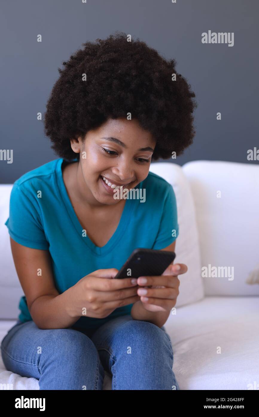 African american woman sitting on sofa using smartphone Stock Photo - Alamy