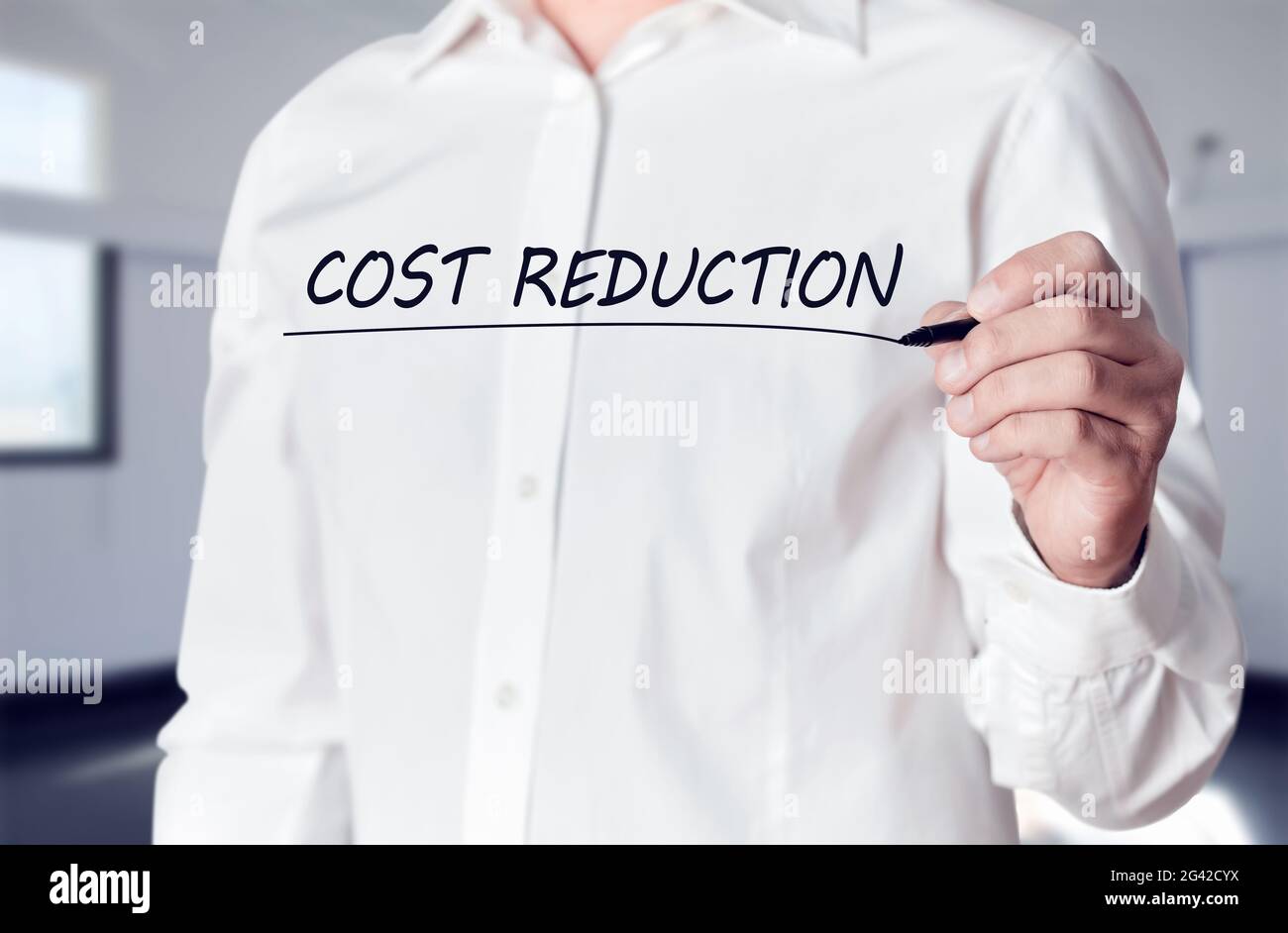 Businessman hand holds a pen and underlines the words cost reduction on a virtual screen. Business finance concept. Stock Photo