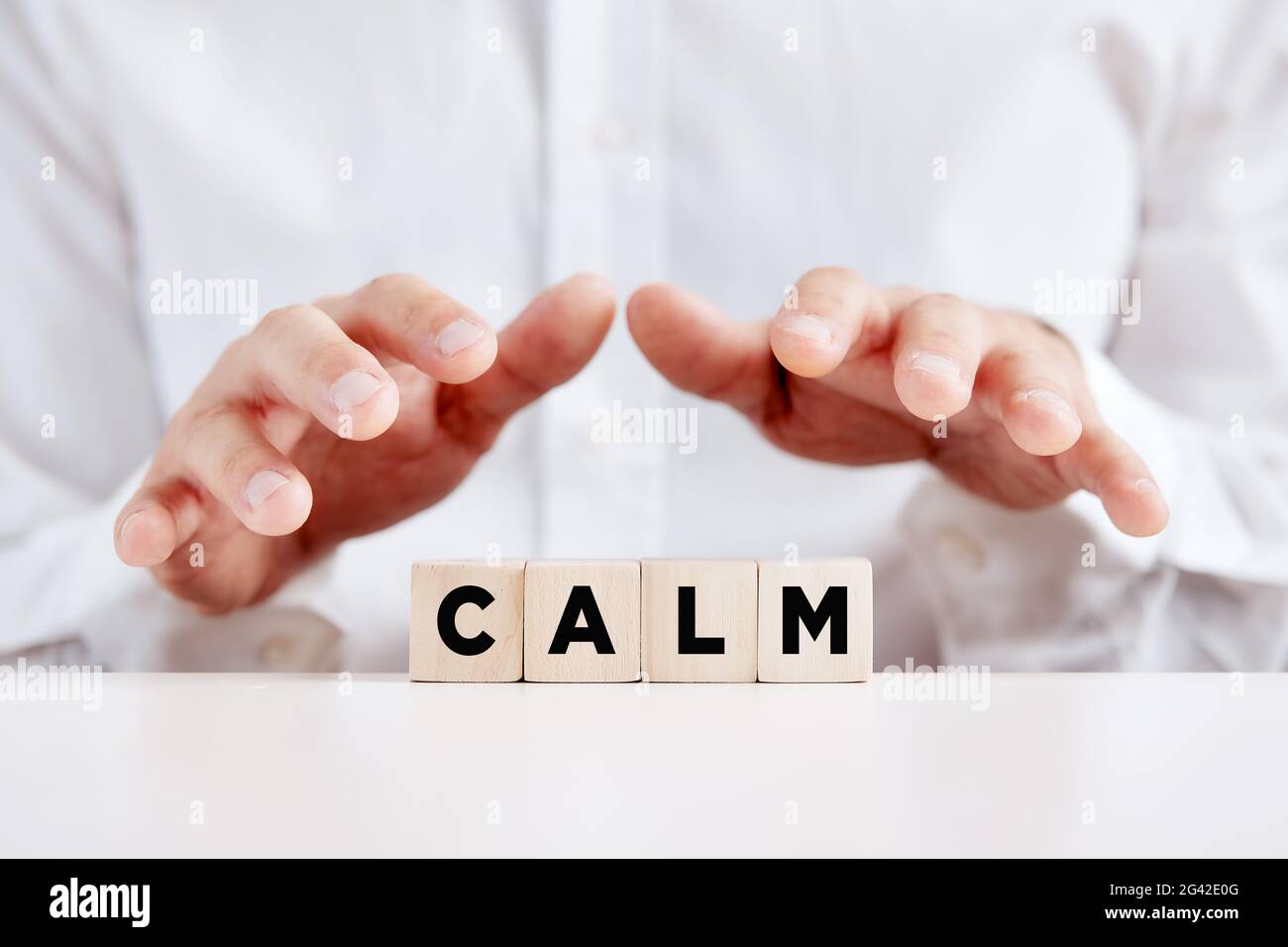 Man holding his hands over the wooden cubes with the word calm. Keep calm, tranquility concept. Stock Photo