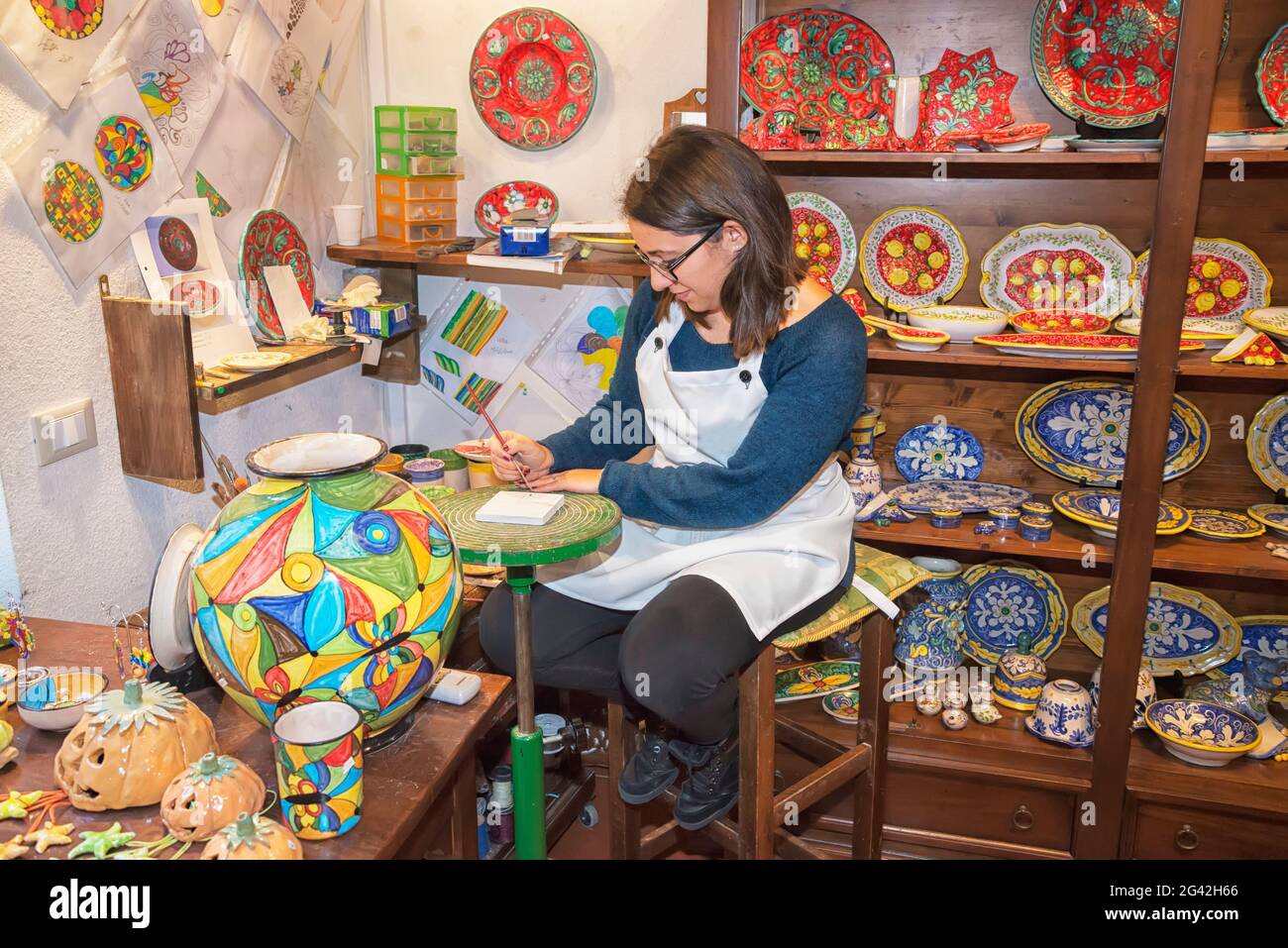 A craftswoman hand painting traditional ceramics, Erice, Sicily, Italy