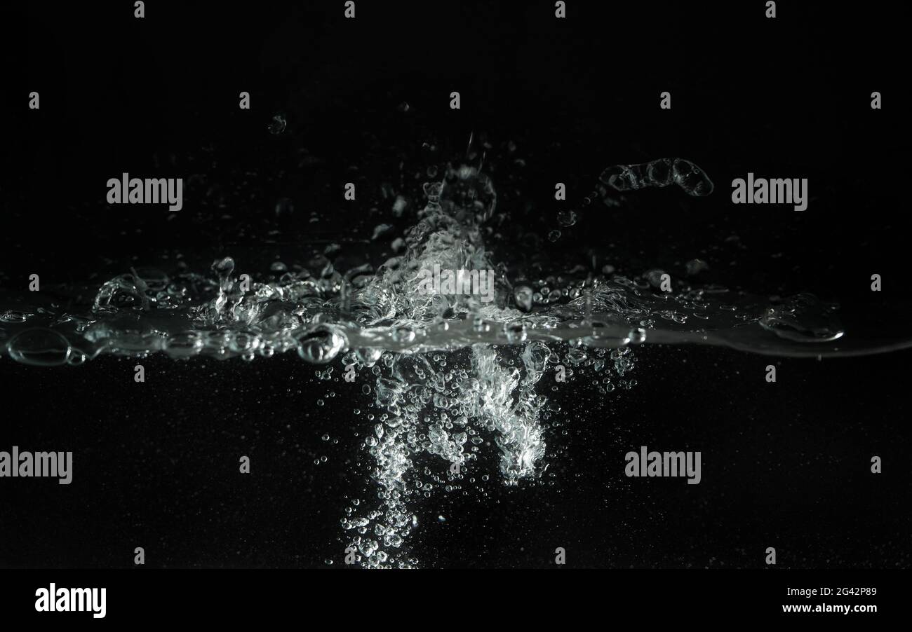Water splashing as it's poured into aquarium tank, black background