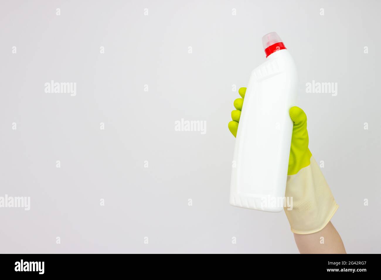 Spring cleaning concept. Top view of hand in yellow rubber gloves holding bottle of detergent on grey background. Cleaning supplies concept Stock Photo