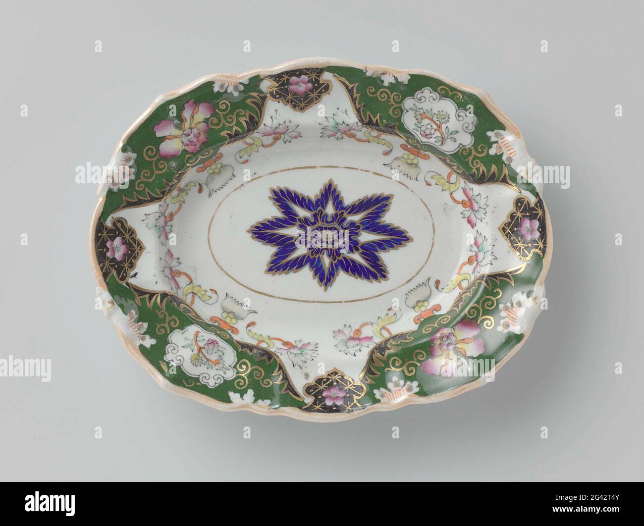 Scale, originally with ears, painted multi-colored with flowers and tendrils. Scale of porcelain, originally with ears (clamped) and multi-colored painted with flowers and tendrils in the colors pink, green, red and yellow with black and gold, partly on dark green soil. In the middle a rosette from Bleu Foncé. Signature: Mason's Patent Ironstone China. Stock Photo