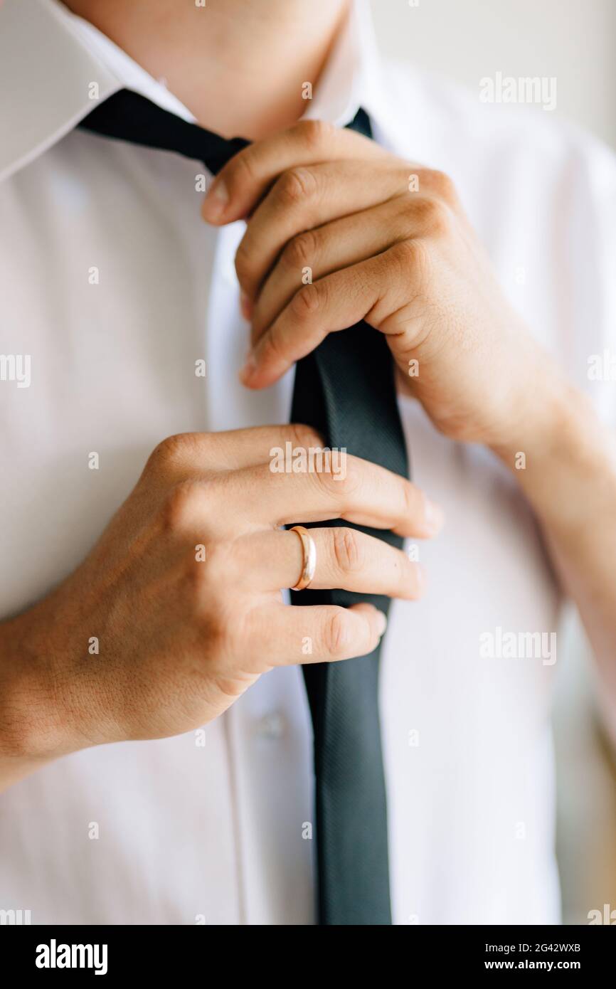 A man puts on and ties a tie while preparing for a wedding ceremony, close-up Stock Photo