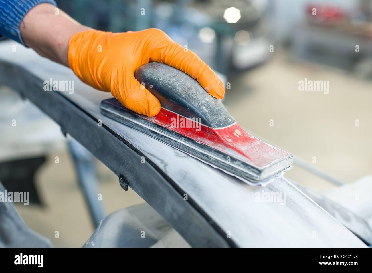 Preparation for painting a car bumper. Hand in a glove with a grinding