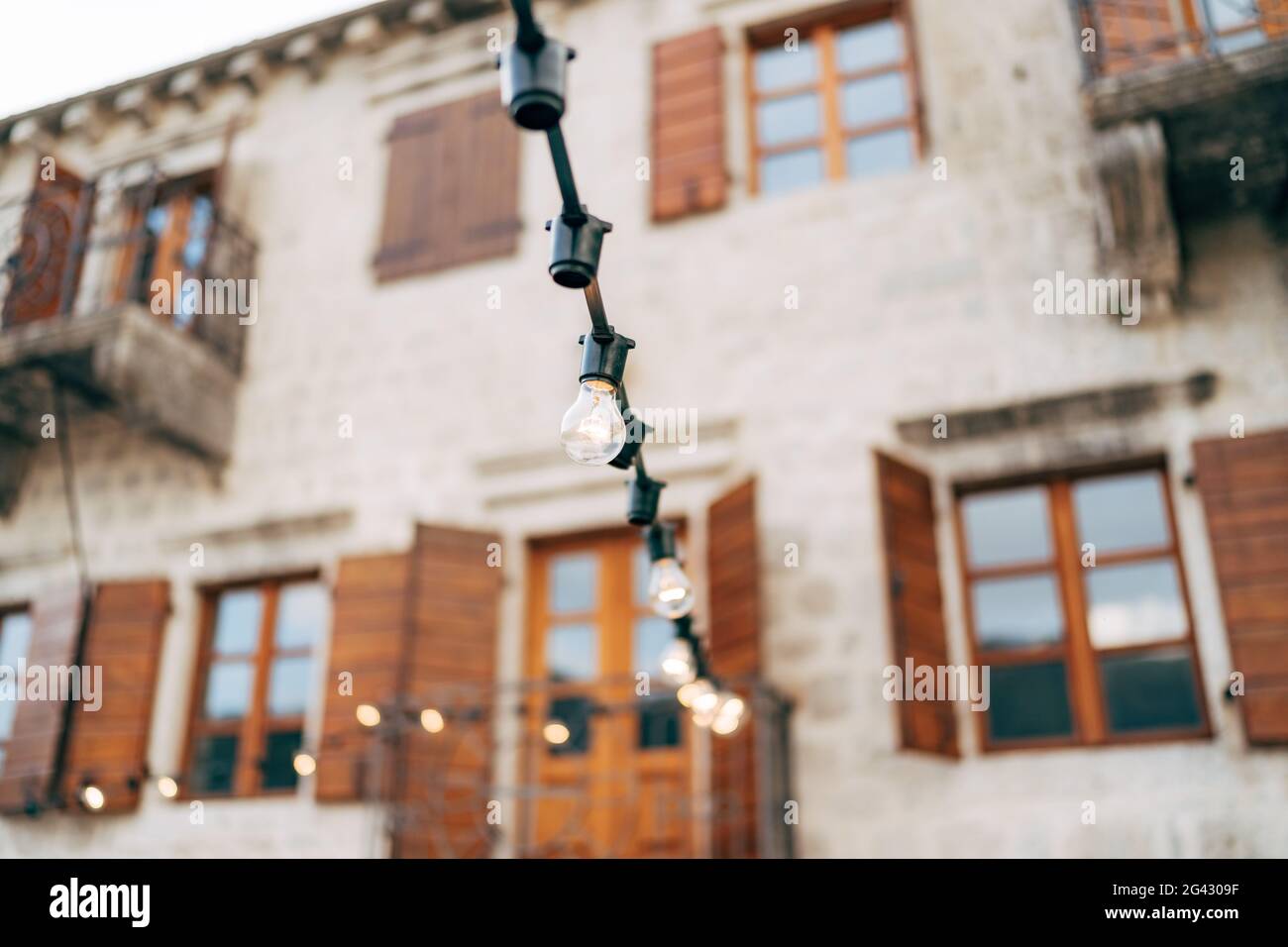 Garland of incandescent lamps against the background of the old villa. Stock Photo