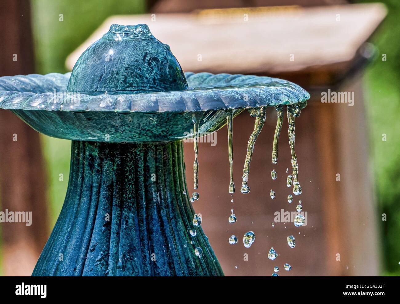 Water seeps over the rim of a garden fountain Stock Photo