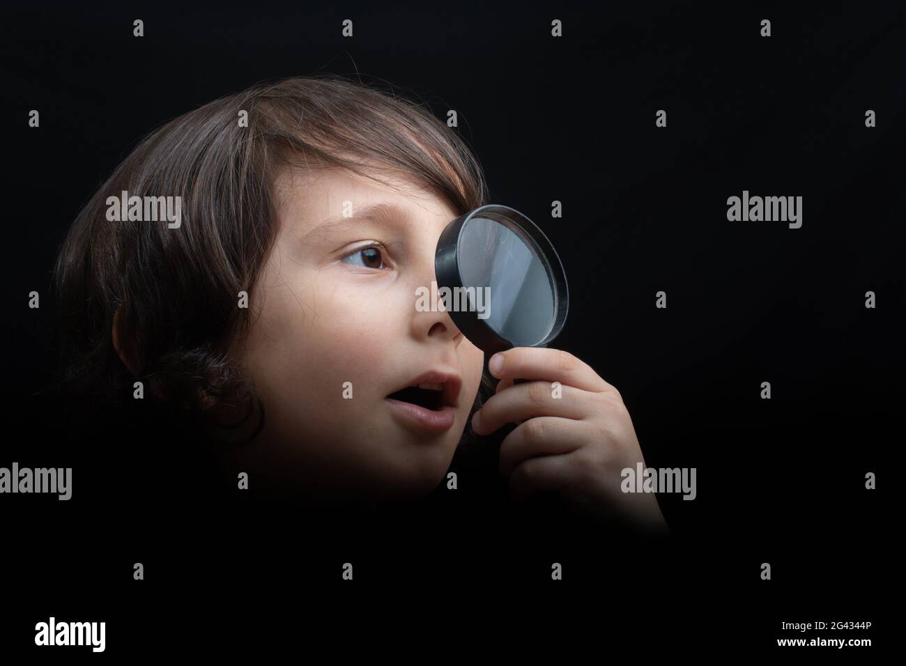 Portrat of a young boy looking through the magnifying glass Stock Photo