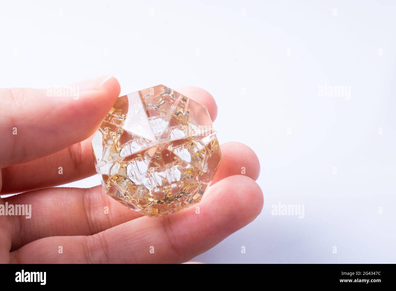 Hand holding a transparent diamond on white background Stock Photo