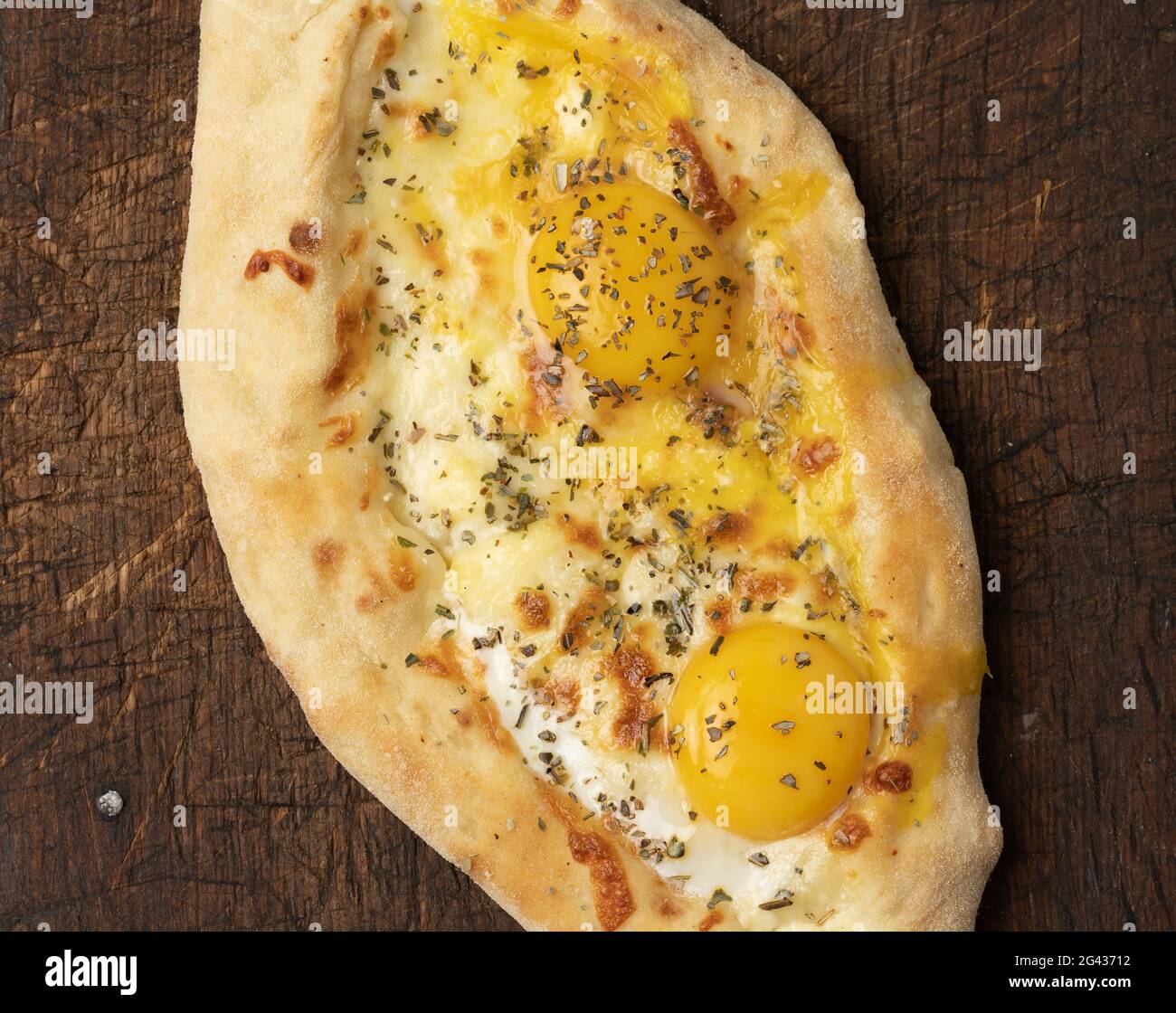 Baked adjarian khachapuri with whole egg yolk on wooden board Stock Photo