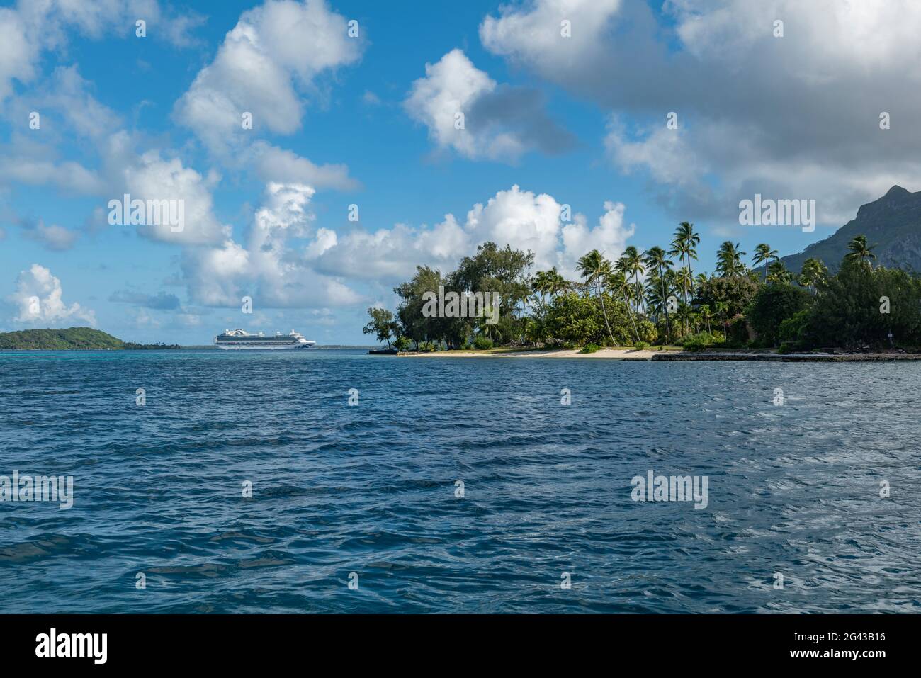 Cruise ship in roadstead in the lagoon of Bora Bora with coconut palms and beach on island, Bora Bora, Leeward Islands, French Polynesia, South Pacifi Stock Photo