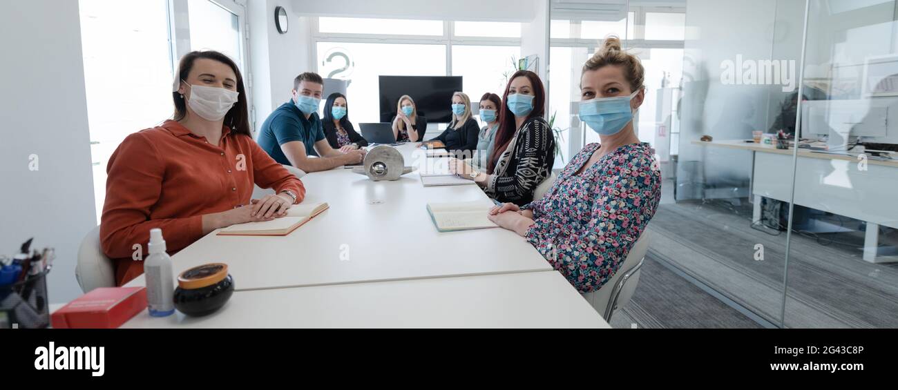 Real business people on meeting wearing protective mask Stock Photo