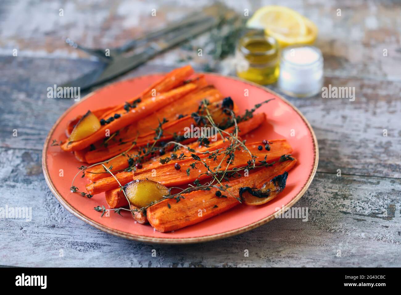 A plate with baked carrots. Baked carrots in strips with herbs and spices. Stock Photo