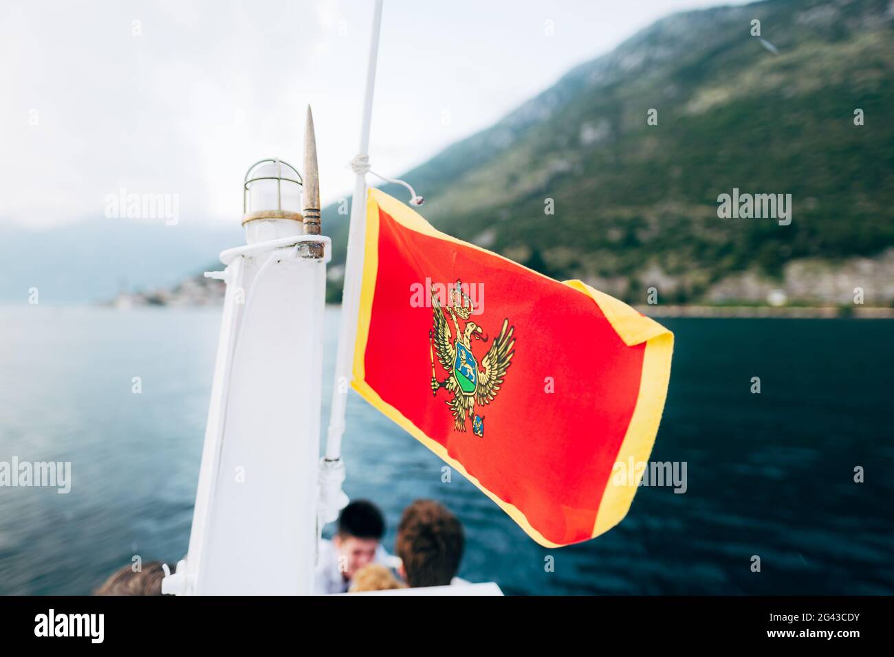 Montenegro flag in red on a flagpole on a yacht sailing along the coast. Stock Photo