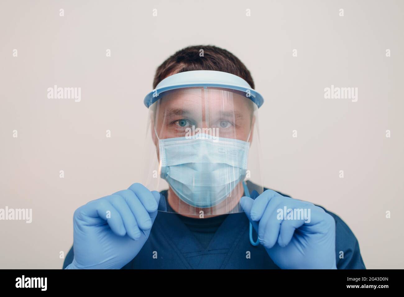 Man in face medical surgical mask with transparent shield mask and gloves Stock Photo