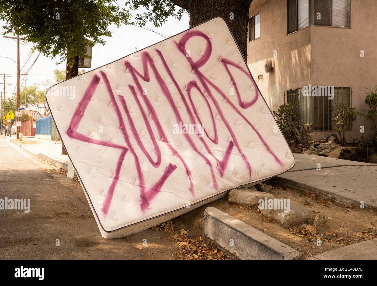 Mattress with graffiti reading 'slumlord' in the Highland Park neighborhood of Los Angeles, California. Stock Photo