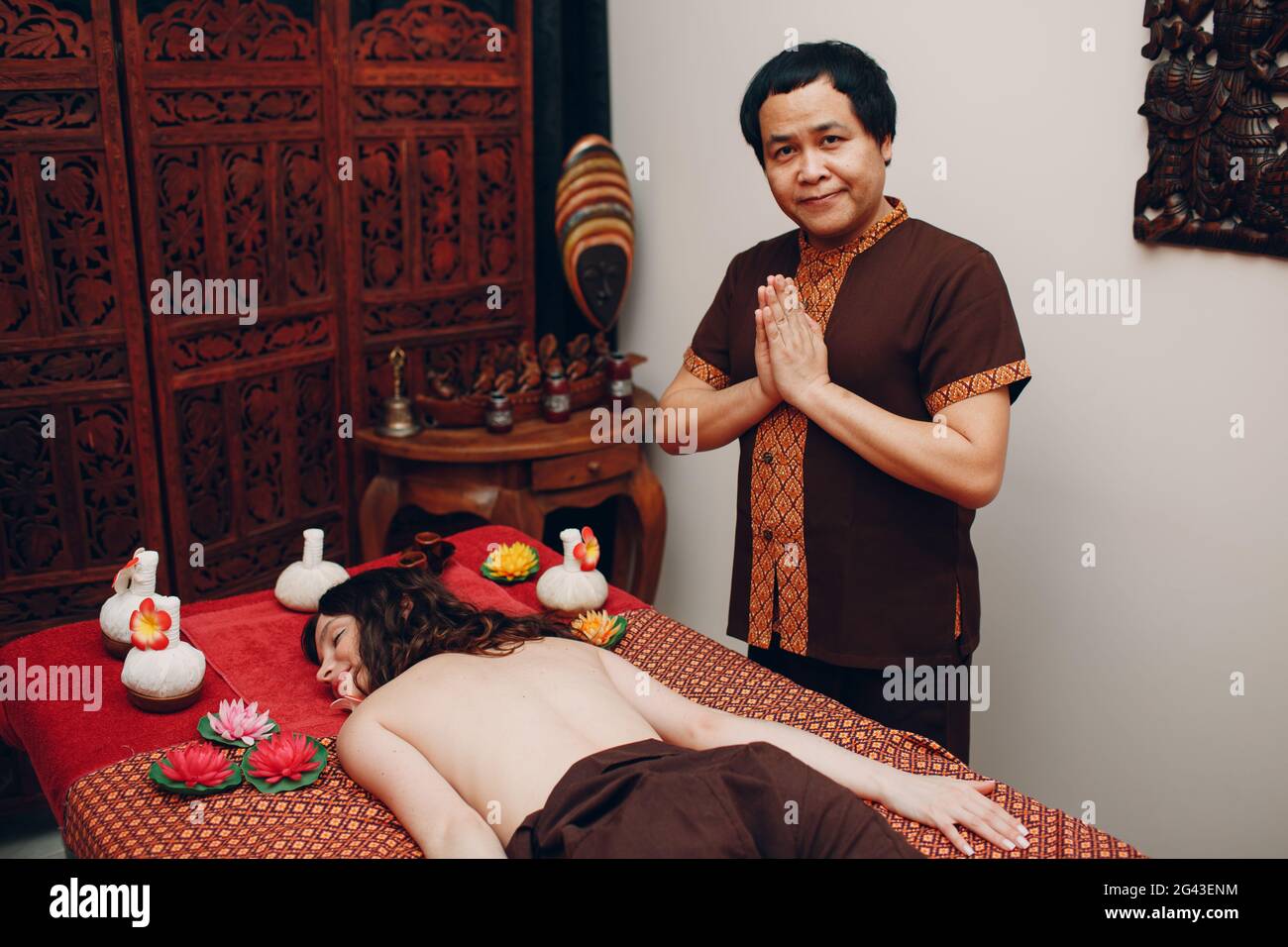 Thai man making classical thai massage procedure to young woman at beauty spa Stock Photo